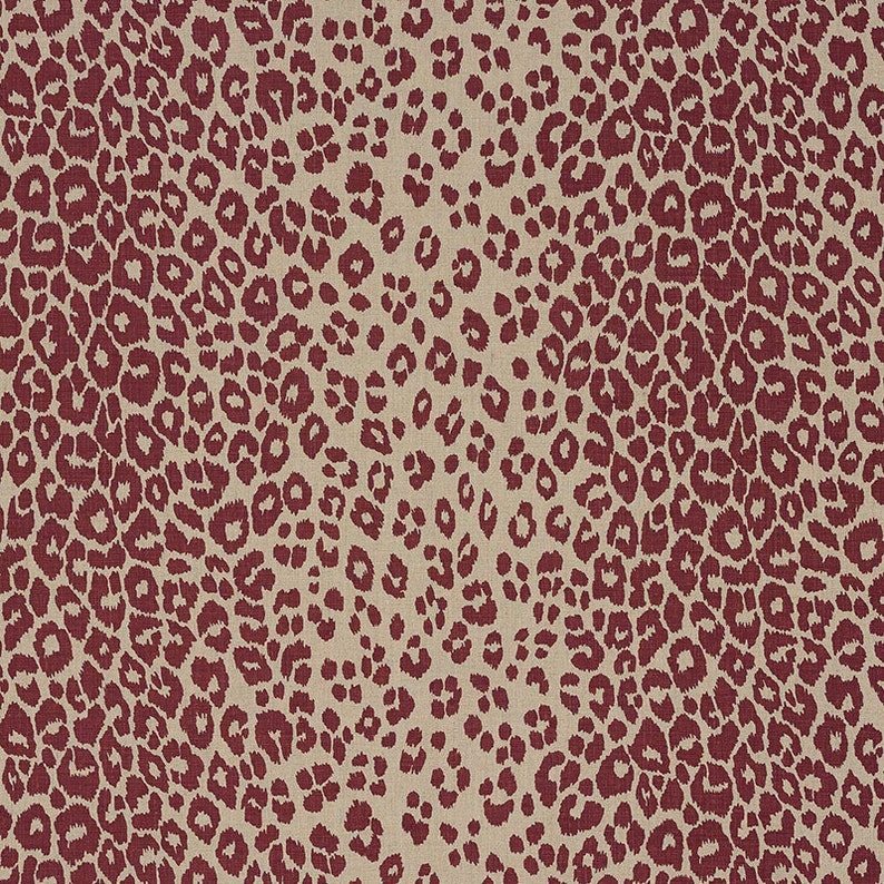 May include: A beige fabric with a red leopard print pattern. The print is a repeating pattern of red spots on a beige background.
