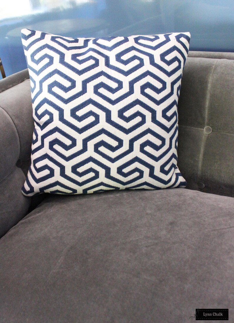 May include: A white and navy blue geometric patterned throw pillow. The pillow is on a gray couch.