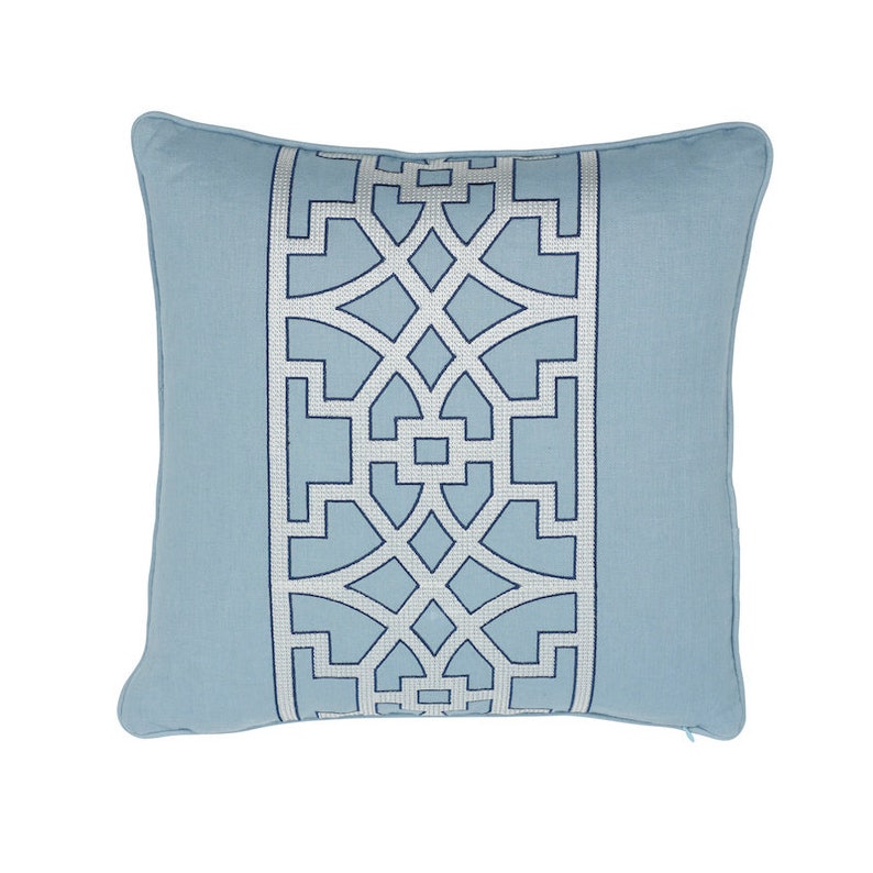 K&ouml;nnte beinhalten: Ein hellblaues Kissen mit einem wei&szlig;en und blauen geometrischen Muster. Das Muster ist ein sich wiederholendes Design aus Quadraten und Kreisen.