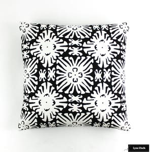 Puede incluir: Coj&iacute;n cuadrado con un estampado floral en blanco y negro. El dise&ntilde;o presenta formas de flores estilizadas repetidas en negro sobre un fondo blanco. El coj&iacute;n es cuadrado y parece estar hecho de tela.