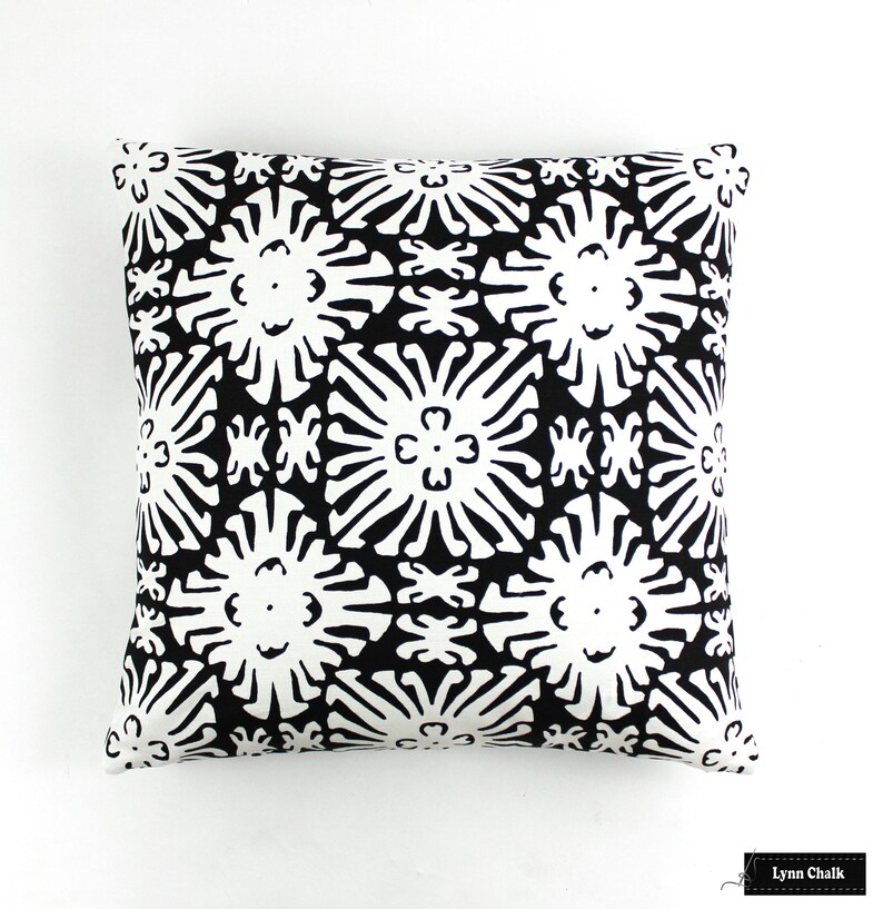 Puede incluir: Coj&iacute;n cuadrado con un estampado floral en blanco y negro. El dise&ntilde;o presenta formas de flores estilizadas repetidas en negro sobre un fondo blanco. El coj&iacute;n es cuadrado y parece estar hecho de tela.