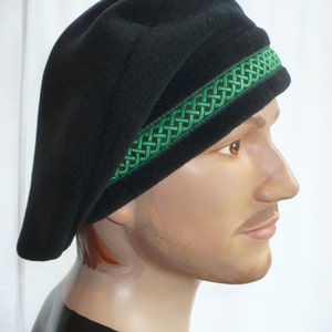 May include: A black beret with a green braided trim. The beret is worn on a mannequin's head.