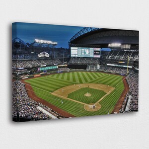 May include: A canvas print of a baseball stadium at dusk. The field is green with brown dirt areas. The stands are filled with spectators. The stadium's name, SAFECO FIELD, is visible in the background.