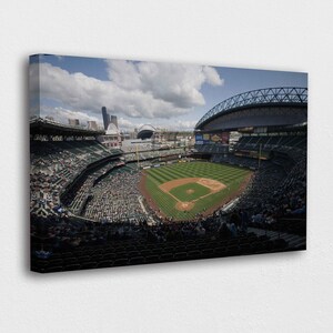 May include: A canvas print of a baseball stadium filled with spectators. The field is green with brown dirt areas. The sky is blue with fluffy white clouds. The stadium has a large arched roof and seating areas filled with people.