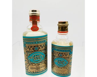 May include: Two vintage bottles of 4711 Original Eau de Cologne. The bottles have gold and teal labels with the text "KÖLNISCH WASSER" and "4711". The larger bottle has a red seal. The bottles are clear and filled with a light-colored liquid.