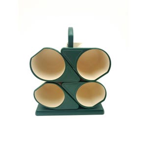 May include: A dark green wine rack with four circular openings and a handle. The interior of each opening is beige. The rack is designed to hold wine bottles and is made of a solid material.