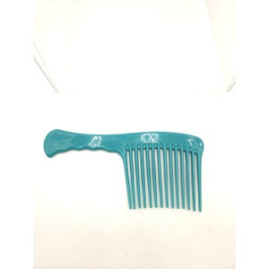 May include: A teal-colored wide-tooth comb with a handle. The comb has a series of evenly spaced teeth and a curved handle for easy grip. The comb is made of plastic and is designed for detangling and styling hair.