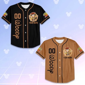 Puede incluir: Dos camisetas de b&eacute;isbol, una negra y otra marr&oacute;n, con un personaje de vaquero de dibujos animados. Las camisetas tienen el n&uacute;mero "00" y el nombre "Woody" impresos, con la opci&oacute;n de a&ntilde;adir un nombre personalizado.