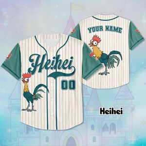 Puede incluir: Camiseta de b&eacute;isbol crema con rayas doradas y mangas verde azulado. La parte delantera presenta "Heihei" en escritura verde azulado y el n&uacute;mero "00". Un gallo de dibujos animados est&aacute; en la parte delantera y trasera. La parte trasera tiene "YOUR NAME" encima del gallo.