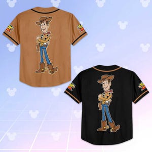 Puede incluir: Dos camisetas de b&eacute;isbol, una marr&oacute;n y otra negra, cada una con una imagen de dibujos animados de Woody de Toy Story en la espalda. Las camisetas tienen mangas cortas con ribetes en contraste y el logo de Toy Story en las mangas.
