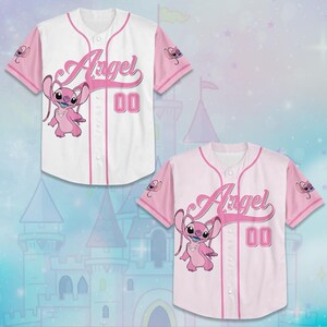 May include: Two baseball jerseys, one white and one pink, featuring the character Angel. The white jersey has pink sleeves and trim, with "Angel" in cursive and the number "00". The pink jersey has white sleeves and trim, with the same design.