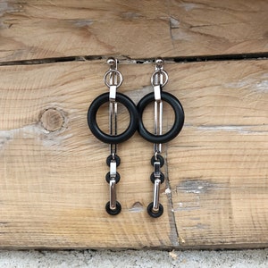 May include: A pair of silver earrings with black circular accents and a chain-like design.