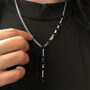 May include: A silver chain necklace with a black and silver chain pendant.
