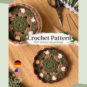 May include: Two handmade crochet coasters with a floral design in shades of green, brown, and white. The text "Crochet Pattern PDF instant download" is displayed. A pair of scissors and crochet hooks are also visible.