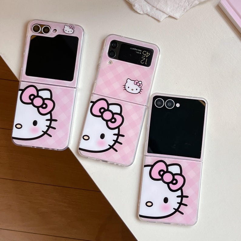May include: Three pink phone cases featuring a Hello Kitty design. The cases are open and closed, displaying the phone's screen and camera. The design incorporates a pink gingham pattern and the Hello Kitty face with a bow.