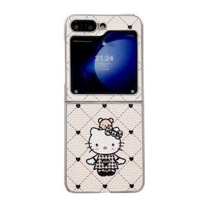 May include: A white, foldable phone case with a quilted pattern and black heart accents. The case features a Hello Kitty graphic with a bear and bow. The phone screen displays the time 21:24.