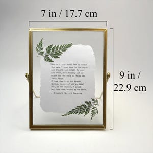 May include: A gold-toned metal framed picture holder, 7 inches wide and 9 inches tall, with a handwritten poem on textured paper. Green fern accents are placed on the paper. The text reads "How do I love thee?"