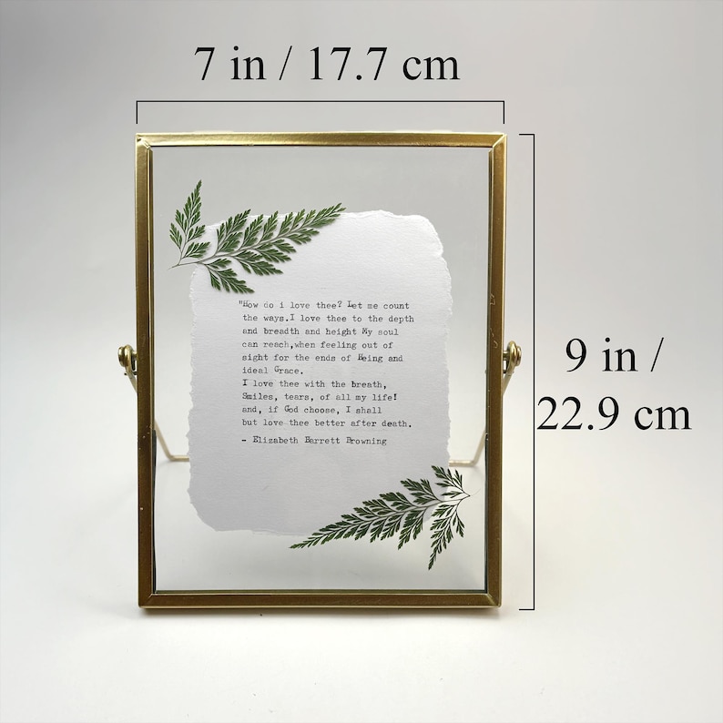 May include: A gold-toned metal framed picture holder, 7 inches wide and 9 inches tall, with a handwritten poem on textured paper. Green fern accents are placed on the paper. The text reads "How do I love thee?"