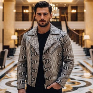 May include: A grey and black snakeskin-patterned leather jacket with a zip closure. The jacket has a classic biker style with a notched collar and asymmetrical zip. The jacket is worn over a black top.