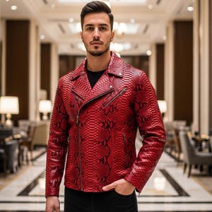 Może przedstawiać: Czerwona skórzana kurtka ze wzorem skóry węża. Kurtka ma klasyczny styl motocyklowy z wykładanym kołnierzem, asymetrycznym zapięciem na zamek i wieloma kieszeniami na zamek. Kurtka jest w żywym czerwonym kolorze.