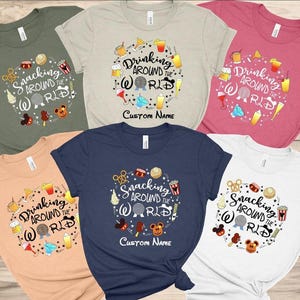 May include: Various coloured t-shirts featuring circular graphics. The designs display the text "Snacking Around the World" and "Drinking Around the World" with food and drink illustrations. Some shirts have a space for a custom name.
