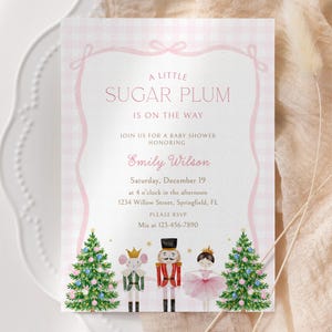 May include: A rectangular baby shower invitation card with a light pink gingham border and a decorative ribbon frame. The text reads A LITTLE SUGAR PLUM IS ON THE WAY, honoring Emily Wilson on Saturday, December 19. Features include two Christmas trees, a mouse, a nutcracker, and a ballerina.
