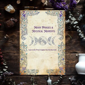 May include: A book titled "Moon Phases & Mystical Moments" with a vintage design, featuring moon phases and floral borders. The cover is cream-colored with purple text and illustrations. The book is surrounded by decorative elements on a wooden surface.