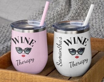 Może przedstawiać: Dwa kieliszki do wina bez nóżki, jeden różowy i jeden biały, z czarnym tekstem i grafiką. Na różowym kubku widnieje napis "WINE Therapy" z okularami przeciwsłonecznymi i czerwonymi ustami. Biały kubek ma napis "Samantha's" i "WINE Therapy". Oba mają słomki.