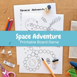 May include: A printable board game titled "Space Adventure" with a blue banner. The game features black and white illustrations of planets, rockets, and astronauts. Colored pencils, dice, scissors, and other craft supplies are scattered around the game.