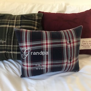 May include: Three plaid cushions, each with embroidered text. One is dark green, another is navy and red, and the third is burgundy. The navy cushion and the green cushion have the word "Grandpa" embroidered on them, along with dates. The burgundy cushion has a tag with text.