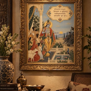 May include: A framed painting depicting a blue-skinned figure in yellow robes standing before a group of people and white cows. The artwork features Sanskrit text in a decorative border, a fountain, and a peacock, all encased in an ornate gold frame.