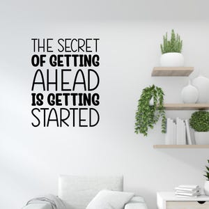 May include: A white wall with the black text, "THE SECRET OF GETTING AHEAD IS GETTING STARTED." The wall also features decorative shelves with plants and books, creating a minimalist aesthetic.