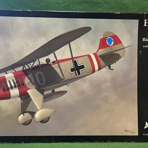 Può includere: Scatola di un kit di modellismo di un aereo Heinkel He-51 Richthofen Squadron. L'aereo è dipinto di rosso, bianco, grigio e nero con il numero 10. La scatola riporta la scritta "HEINKEL He-51 Richthofen Squadron 1/48 SCALE PLASTIC MODEL KIT" e "Classic Airframes".