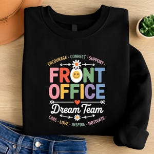 May include: Black sweatshirt with the words "FRONT OFFICE Dream Team" in colorful letters and a smiling face graphic. The design includes the words "Encourage, Connect, Support, Care, Love, Inspire, Motivate."