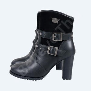 May include: Black leather ankle boots with a block heel. The boots have a suede panel at the top, embellished straps with buckles, and decorative studs. A metal emblem is visible on the suede panel.