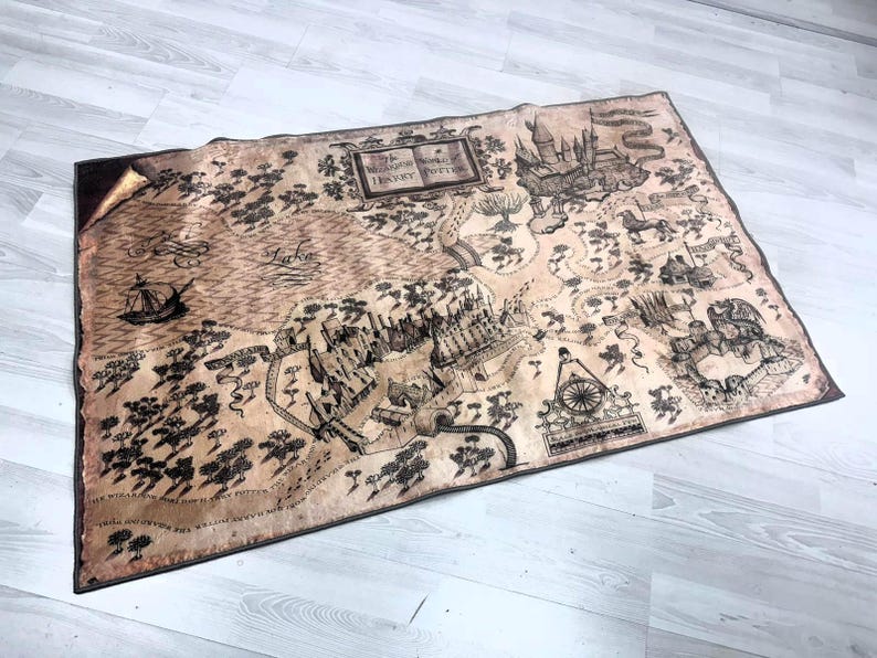 Puede incluir: Un mapa rectangular con apariencia de pergamino, con una detallada ilustraci&oacute;n en negro y marr&oacute;n de un mundo de fantas&iacute;a. El mapa incluye texto, un castillo, un lago y un barco. Es probable que el mapa sea un art&iacute;culo decorativo o un accesorio.