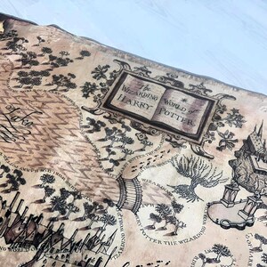 Puede incluir: Un mapa detallado con una est&eacute;tica vintage, con ilustraciones de castillos, &aacute;rboles y caminos. El texto "The Wizarding World of Harry Potter" se muestra de forma destacada. El mapa es de color beige con tinta negra.