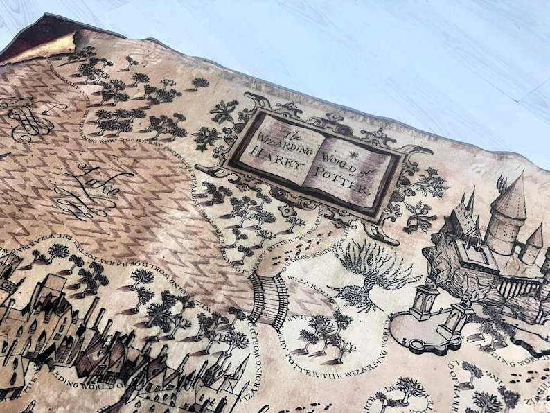 Puede incluir: Un mapa detallado con una est&eacute;tica vintage, con ilustraciones de castillos, &aacute;rboles y caminos. El texto "The Wizarding World of Harry Potter" se muestra de forma destacada. El mapa es de color beige con tinta negra.