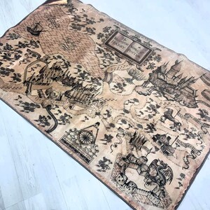 Puede incluir: Un mapa rectangular en tonos marr&oacute;n y beige, que representa un mundo de fantas&iacute;a con castillos, barcos y otras ilustraciones. El mapa incluye el texto "The Marauder's Map" y "Harry Potter". El mapa parece estar hecho de tela.