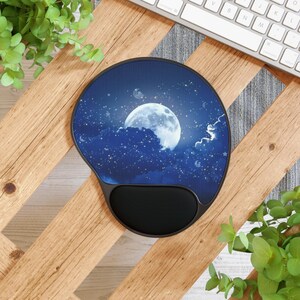 May include: A round mousepad with a black wrist rest. The pad features a nighttime scene with a full moon, clouds, and stars in shades of blue and white. The mousepad is on a wooden surface.