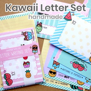 May include: A Kawaii letter writing set with pastel colours and cute illustrations. The set includes envelopes, stationery, and stickers with ice cream, fruit, and other fun designs. The text on the set says "handmade" and "Letter Writing Set".