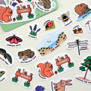 May include: A selection of illustrated stickers depicting British wildlife and landscapes. Stickers include a red squirrel, a ladybird, a dragonfly, and a bumblebee. Some stickers have text, including "FORMBY" and "SAND DUNES".
