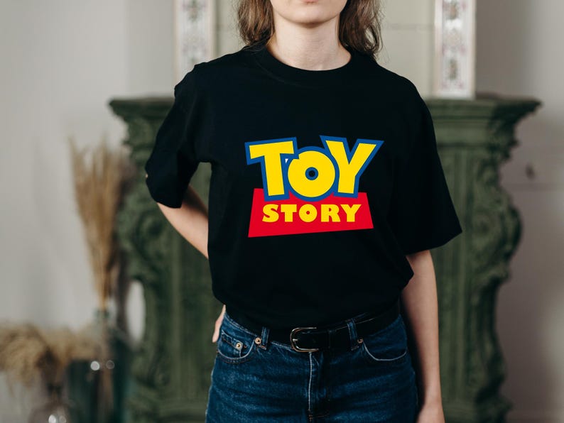 May include: Black t-shirt featuring the "Toy Story" logo in yellow, red, and blue. The shirt has a crew neck and short sleeves. The text "TOY STORY" is prominently displayed on the front.