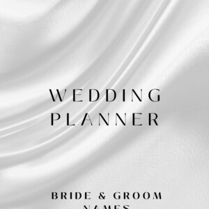 May include: A wedding planner cover with the text "WEDDING PLANNER" in a bold, elegant font. Below, the text "BRIDE & GROOM NAMES" and the date "03.05.2025" are displayed. The background is a flowing, white fabric.