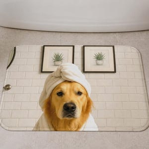 May include: A Golden Retriever wearing a white towel turban and robe, posing on a bathroom mat. The mat is in front of a white brick wall with two framed botanical prints. A wicker basket with white towels and slippers are nearby.