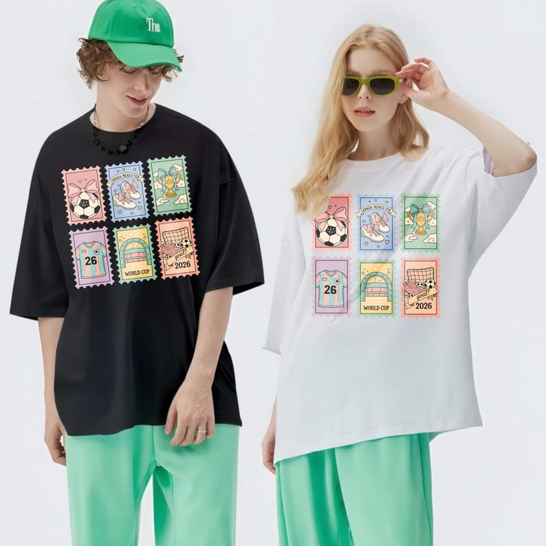 May include: Black and white t-shirts with a colorful stamp design featuring soccer balls, shoes, trophies, and soccer goals. The shirts have short sleeves and are paired with green pants. The stamps include the number "26" and the text "WORLD CUP 2026".