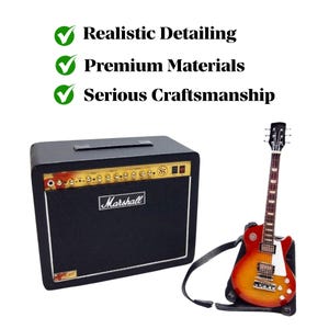 May include: Miniature black guitar amplifier with gold accents and the "Marshall" logo. A miniature electric guitar in red and orange rests on a stand next to the amplifier. The image includes text: "Realistic Detailing, Premium Materials, Serious Craftsmanship."