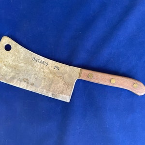 May include: A vintage cleaver with a wooden handle and brass rivets. The blade is marked "ONTARIO 1 1/4".