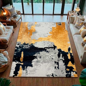 Puede incluir: Una alfombra rectangular grande con un diseño abstracto. La alfombra presenta una mezcla de colores, incluyendo amarillo mostaza, gris y azul marino. El diseño tiene una apariencia texturizada y pictórica, adecuada para una sala de estar. Dimensiones: aprox. 240 x 300 cm.