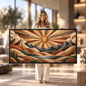 Puede incluir: Una pieza de arte mural rectangular que presenta un paisaje geométrico con incrustaciones de madera. El diseño muestra un sol central con rayos radiantes sobre picos montañosos estilizados, colinas y un cuerpo de agua en tonos madera.